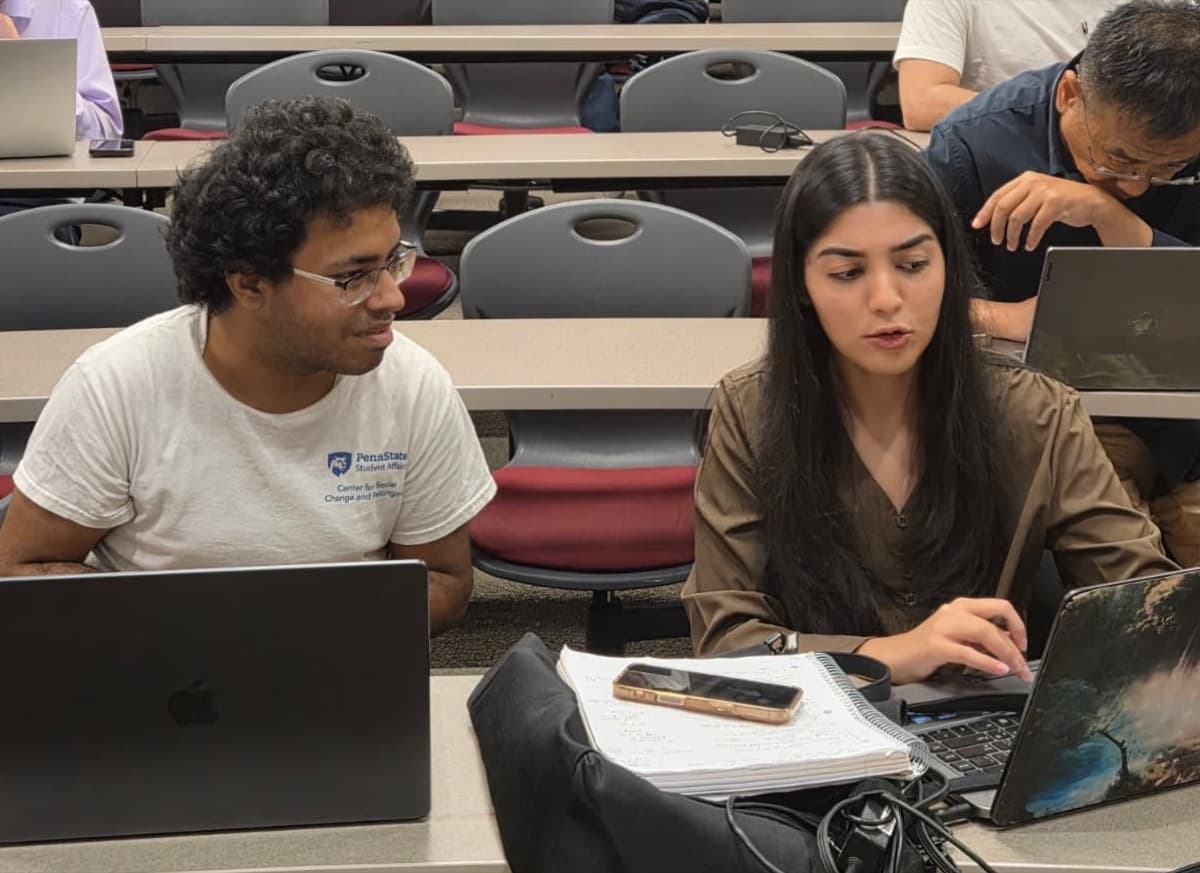 Two attendees working together on a laptop