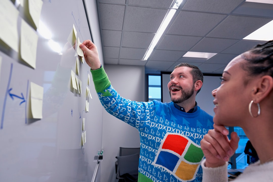man wearing blue Windows sweater holding sticky note on white board - Photo by Windows on Unsplash
